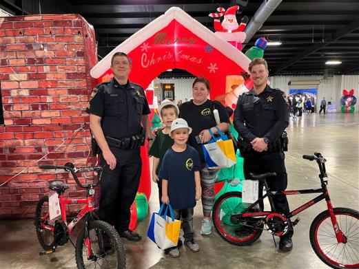 Photo of two deputies at OBE standing with a mother and two young boys with their new bicycles.